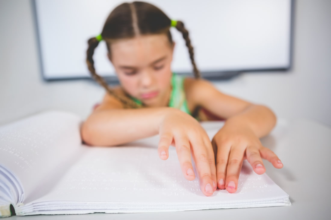 A child reads braille on paper. Photo