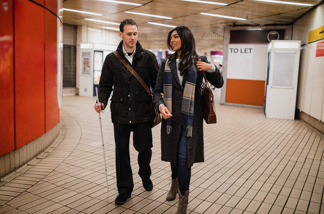 A blind person with white person guided by a companion. Photo