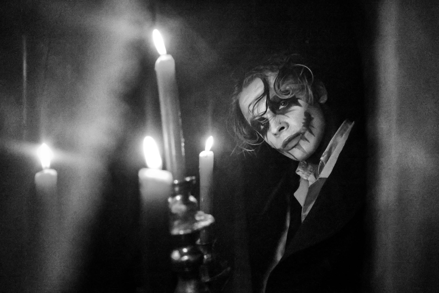 Na ČB obrázku je "Joker", okolo neho horiace sviečky.