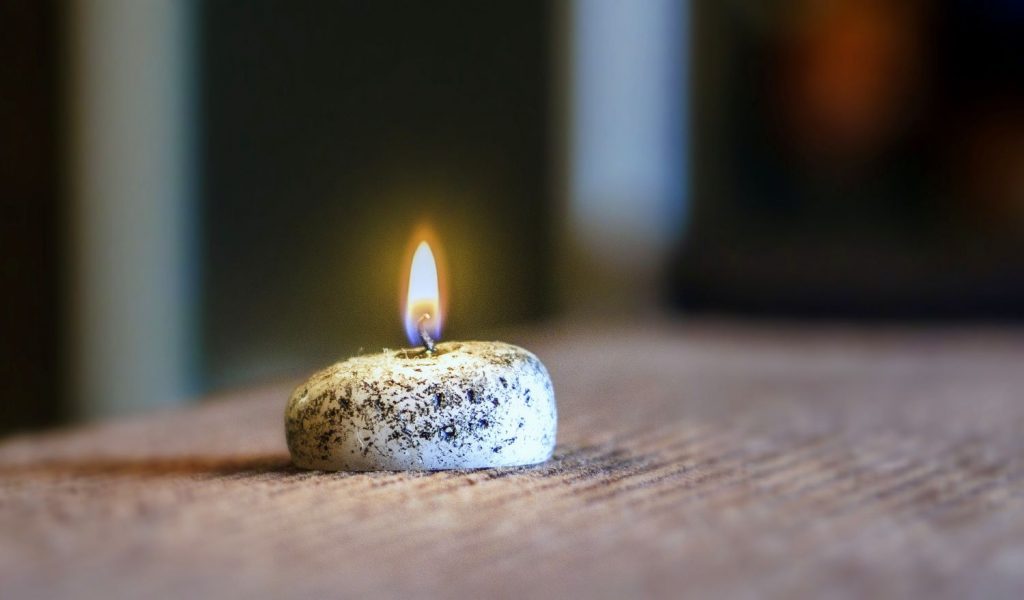 Detail horiacej sviečky. Vyzerá akoby z kamienka horel plamienok.