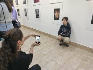 Chlapec čupí pri fotografii a díva sa do objektívu MT, ktorým ho fotí mama.