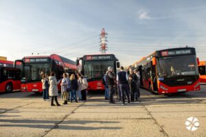 Na obrázku sú tri autobusy MHD s označením Ahoj, Bratislava a pred nimi dva hlúčiky ľudí - pracovníci DPB i ľudia s bielou palicou či bez nej.