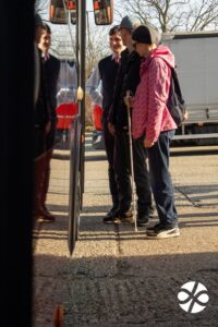 Na obrázku stoja pred vchodovými dverami autobusu usmiaty vodič, muž a žena s bielou palicou.
