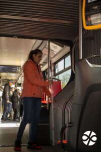 Mladá žena s bielou palicou rukami prehmatáva spoj vo vnútri autobusu, tzv. kĺb.