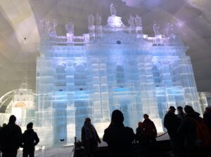 Bazilika z ľadu, na ktorej sú na vrchu ľadové sochy svätcov. Pred ňou vidno postavy návštevníkov. 