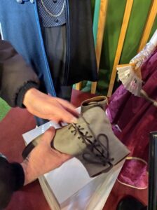 Ruky prezerajúce si dobové topánky - akoby kotníkové čižmy so šnurovaním. 