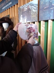 Ruky prezerajúce si dobový klobúk ozdobený látkovými kvetmi. 