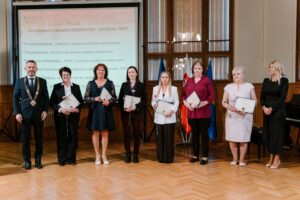 Na obrázku sú ocenené dámy, stoja na pódiu a v rukách držia diplomy. Pri nich stojí župan NSR. Za nimi je obrazovka, kde vidno text: Nominované v kategórii ZDRAVOTNO-SOCIÁLNY ÚSEK a mená nominovaných žien