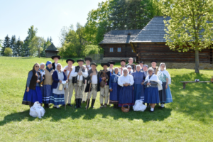 Na obrázku sú v múzeu Slovenskej dediny ženy a muži oblečený v tradičných krojoch. 