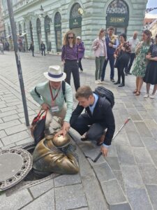 V centre fotografie je vidno, ako si Lars Bosselmann rukami pozerá známu sochu Čumila - jednu z najpopulárnejších turistických atrakcií v historickom centre mesta. Ide o bronzovú sochu muža vyzerajúceho zo zloženými rukami z kanálového poklopu. Za ním postáva zvyšok skupinky.