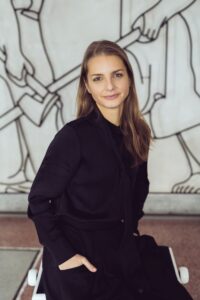 Na obrázku je mladá žena v čiernej blúzke, s jemným úsmevom sa díva do objektívu.